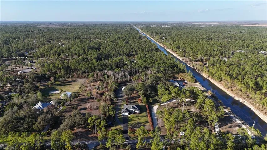 Aerial overview of property's location featuring a forest and a large body of water