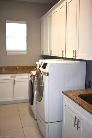 Laundry room with cabinet space, light tile patterned floors, and washing machine and dryer