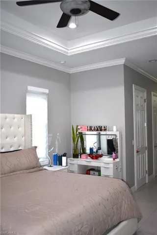 Bedroom featuring ornamental molding, ceiling fan, and a tray ceiling