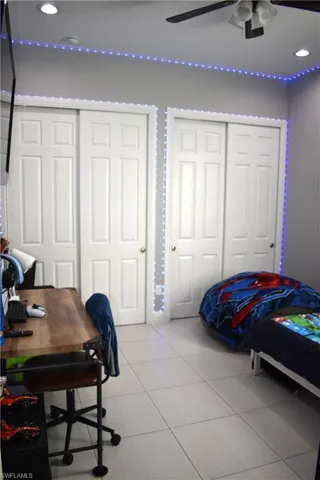 Bedroom with two closets, recessed lighting, light tile patterned floors, and ceiling fan