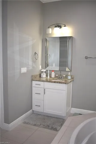 Bathroom featuring vanity, light tile patterned floors, and a bath
