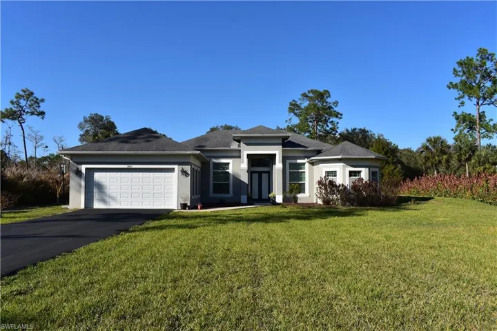 View of front of property featuring a front lawn, a garage, stucco siding, and asphalt driveway