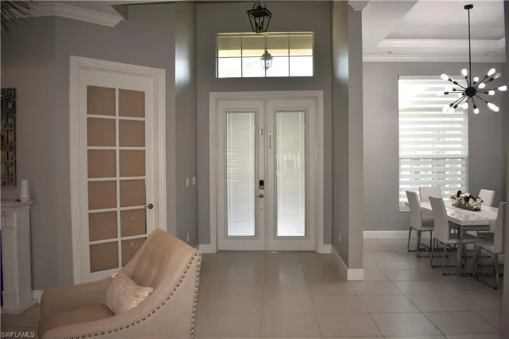 Foyer featuring crown molding, french doors, suspended lighting, and light tile patterned flooring