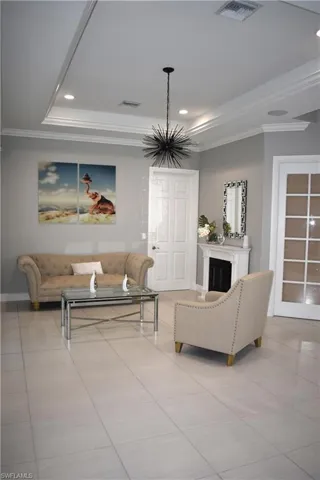Living area with ornamental molding, light tile patterned floors, a raised ceiling, and suspended lighting