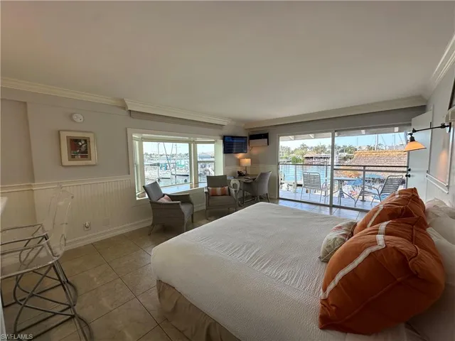 Bedroom featuring access to exterior, a water view, ornamental molding, and light tile patterned flooring