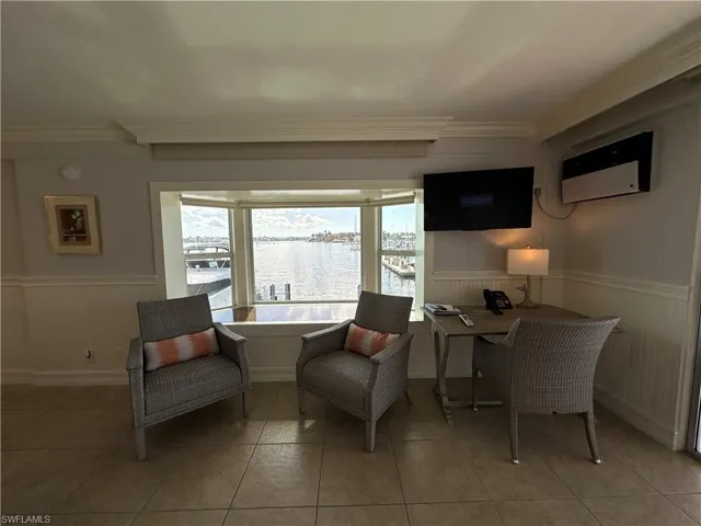 Sitting room with ornamental molding, light tile patterned floors, and a wall mounted AC