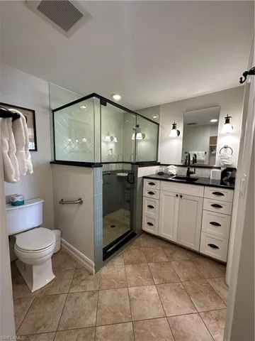 Bathroom with vanity, toilet, tile patterned floors, and a shower with door