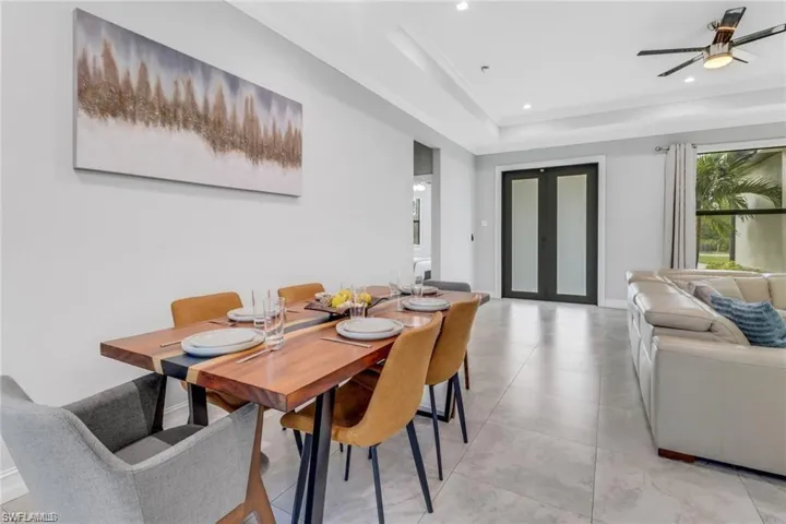 Dining room with french doors, a ceiling fan, recessed lighting, crown molding, and a raised ceiling