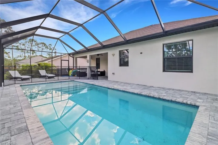 View of pool featuring a sunroom, glass enclosure, and patio surround