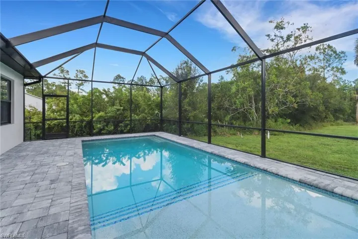 Swimming pool with a yard, a sunroom, glass enclosure, and a patio