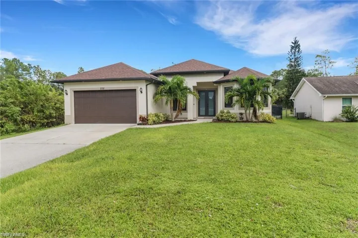 View of front of home featuring a front lawn, stucco siding, an attached garage, and concrete driveway