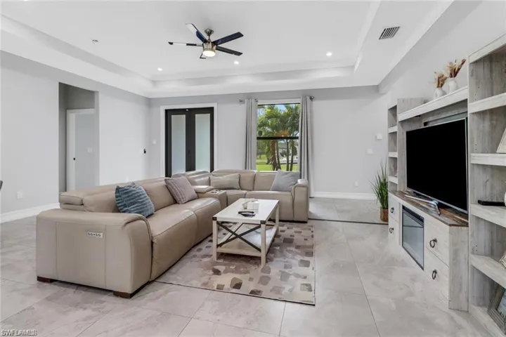 Living area featuring a ceiling fan, recessed lighting, and a raised ceiling