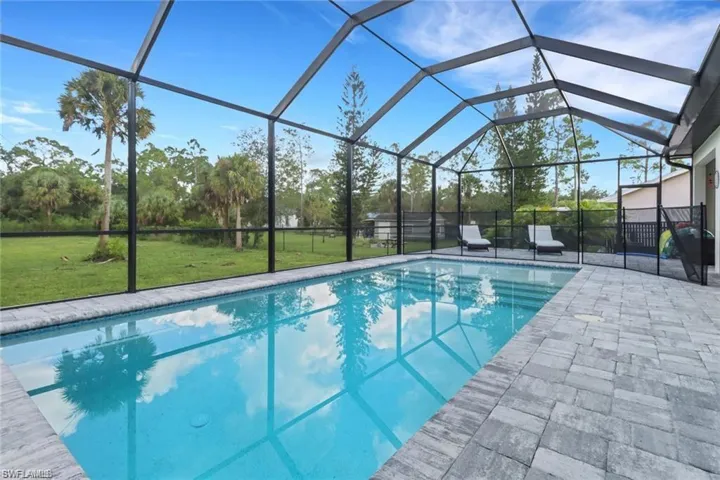 Swimming pool featuring a sunroom, a yard, glass enclosure, and a patio