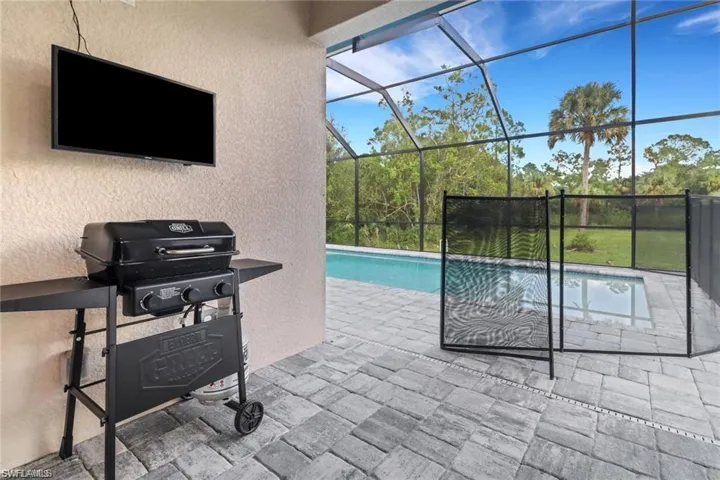 Swimming pool featuring area for grilling, a patio area, a sunroom, and a lanai