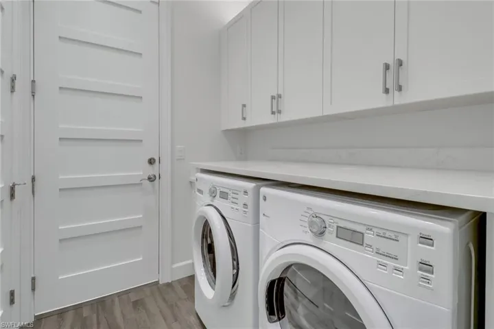 Laundry area featuring light wood-type flooring, washer and dryer, and cabinets