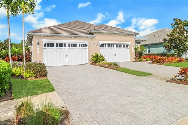 View of front of property with a tiled roof, a garage, decorative driveway, and stucco siding
