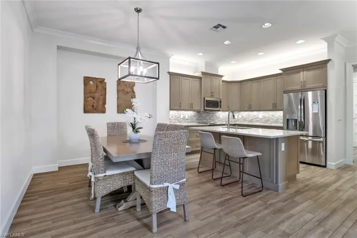 Dining room with an inviting chandelier, hardwood / wood-style flooring, crown molding, and sink