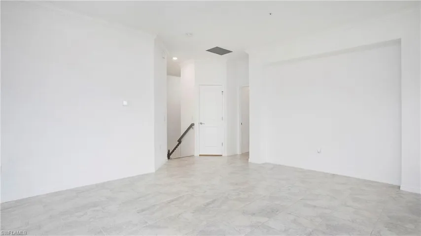 Open-concept living space featuring light-toned tile flooring, recessed lighting, and crisp white walls