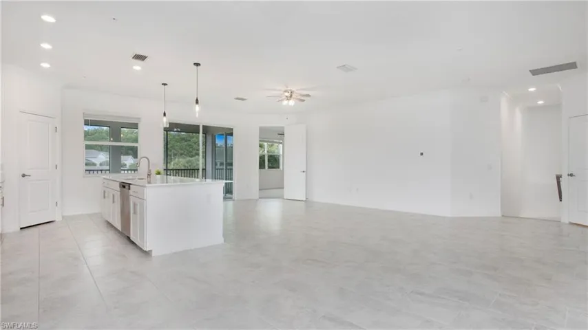 Spacious open-concept living area featuring light-toned tile flooring, recessed lighting, and a ceiling fan