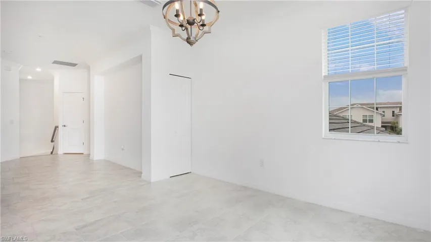 Spacious interior featuring light-colored tile flooring, white walls, and a large window with horizontal blinds