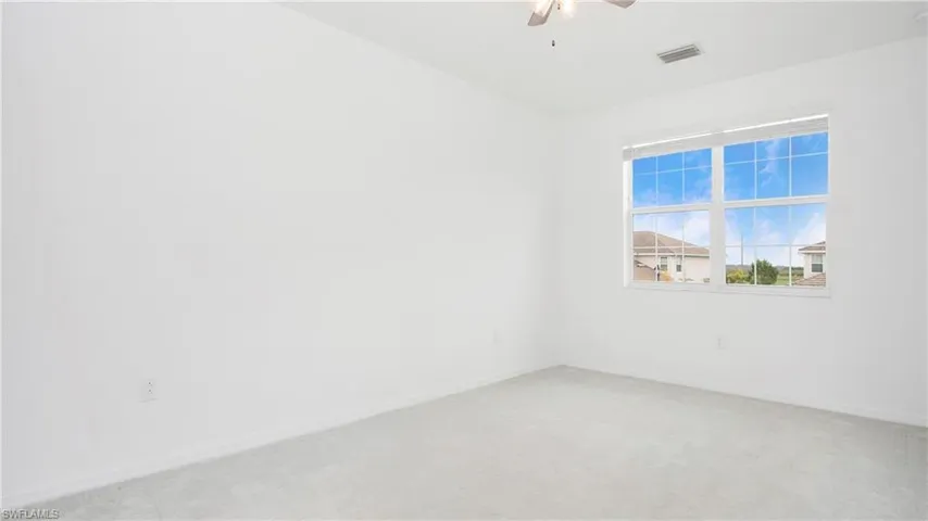 Spacious interior room featuring light gray carpet flooring and white walls