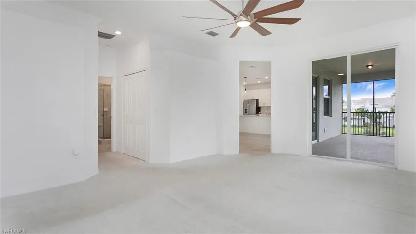 Spacious carpeted room featuring crown molding, a ceiling fan, and sliding glass doors opening to a screened balcony