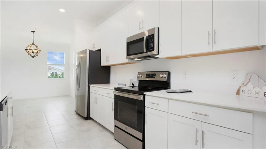 Modern kitchen featuring white shaker cabinetry, stainless steel appliances, and light-toned tile flooring