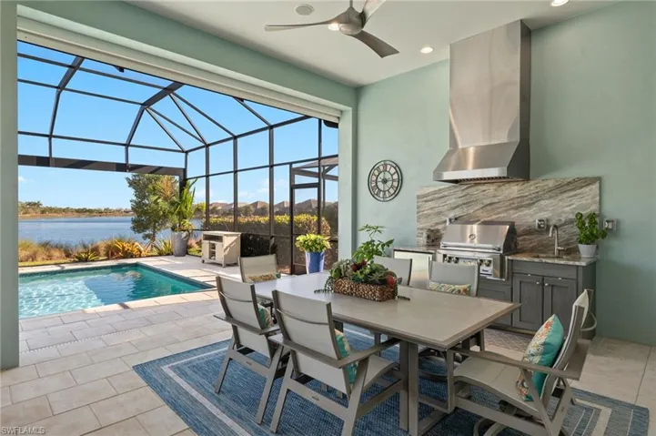 View of pool with a water view, area for grilling, and ceiling fan