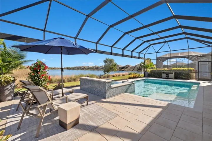 View of pool featuring a water view, a hot tub, a lanai, and a patio area