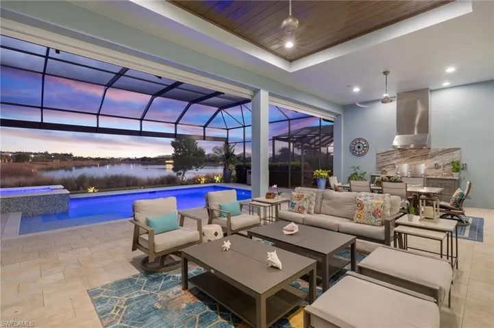 Patio terrace at dusk featuring a swimming pool with hot tub, an outdoor hangout area, and a lanai