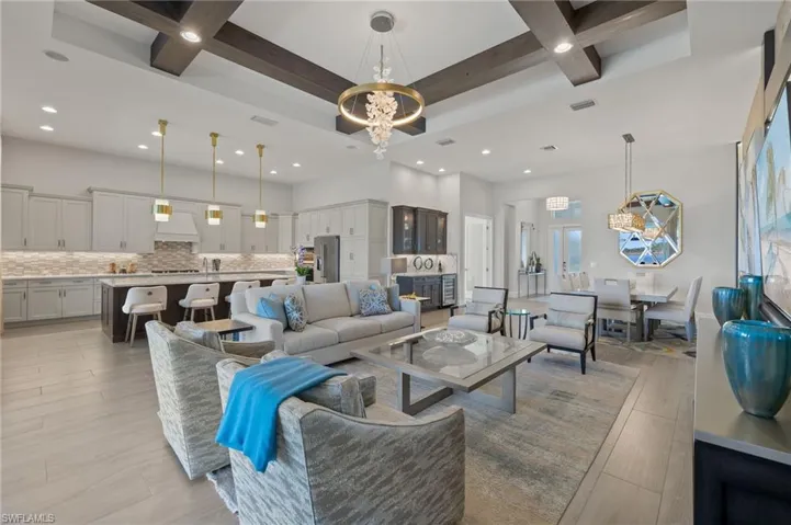 Living room with a chandelier, beamed ceiling, light hardwood / wood-style floors, and coffered ceiling