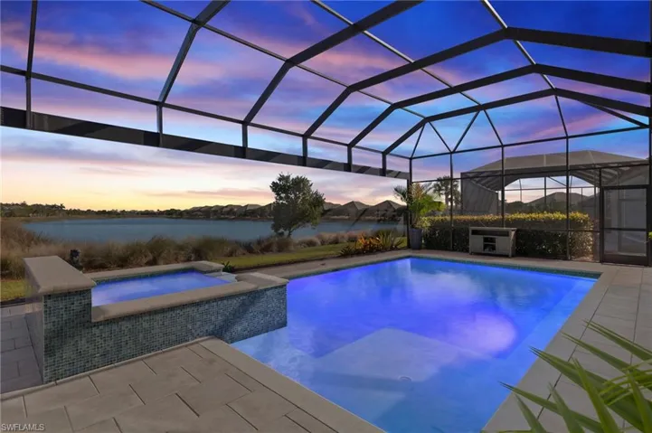Pool at dusk with glass enclosure, an in ground hot tub, and a patio