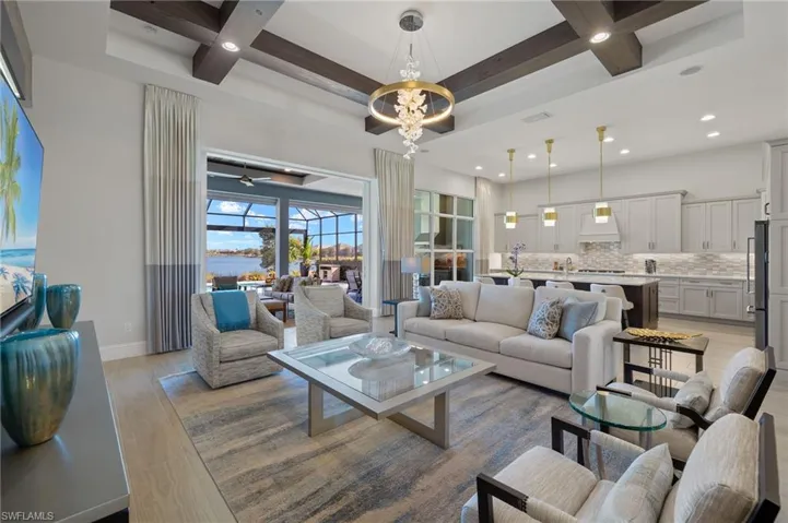 Living room with coffered ceiling, beamed ceiling, ceiling fan with notable chandelier, and light wood-type flooring