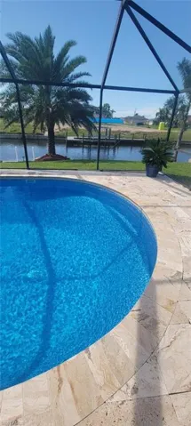 View of pool with a water view and glass enclosure
