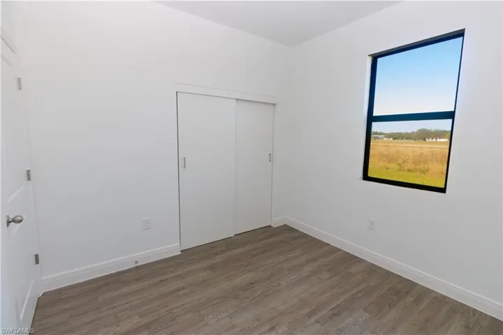 White walls with wood-finish flooring, a contemporary window, and a sliding closet door