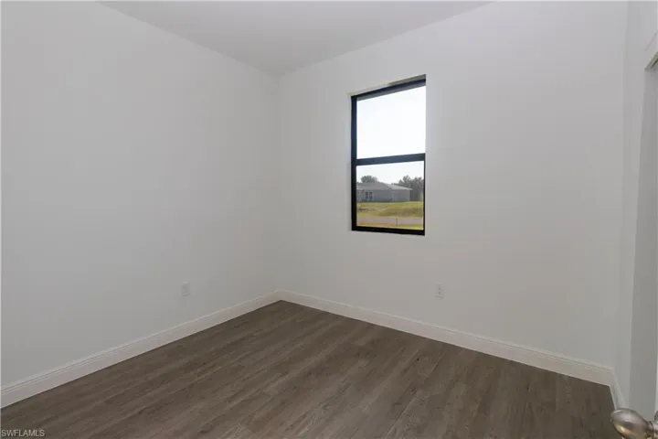 Wood-finish flooring, white walls, and a black-framed window