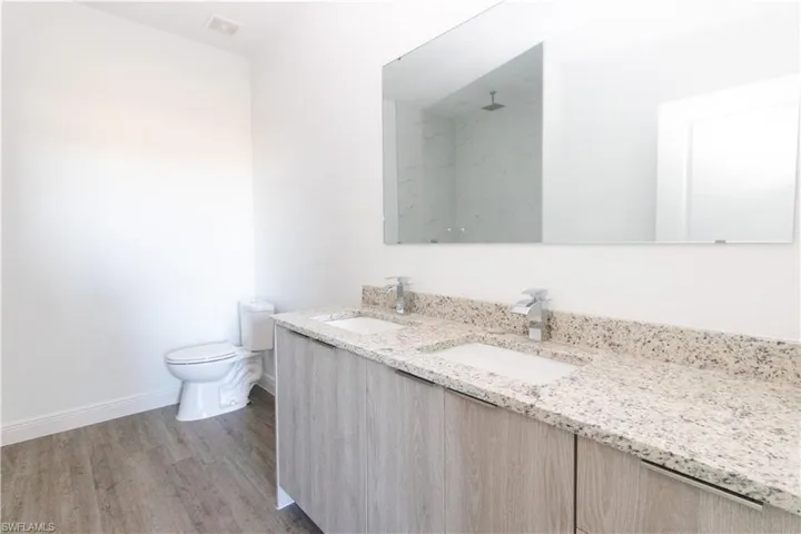 Dual undermount sinks with chrome faucets, speckled countertop, and wood-finish vanity