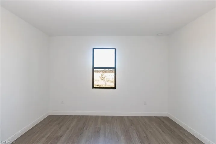 Room featuring wood-finish flooring, a single window with a dark frame, and recessed ceiling lighting