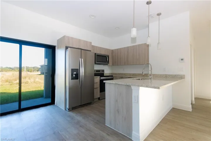 Kitchen featuring wood-finish cabinetry, granite countertops, stainless steel appliances, and pendant lighting