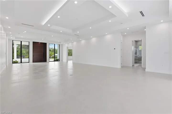Unfurnished room featuring plenty of natural light, a raised ceiling, recessed lighting, and concrete flooring
