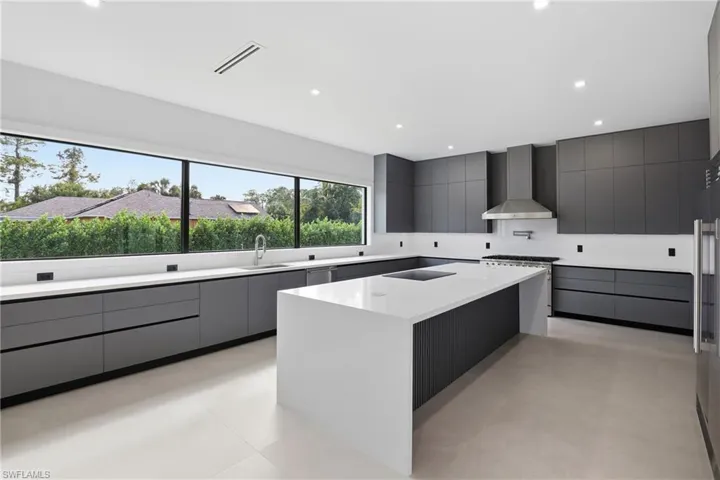Kitchen with gray cabinetry, modern cabinets, recessed lighting, light stone counters, and stainless steel gas range oven