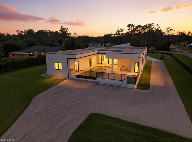 Contemporary house featuring a patio area, stucco siding, driveway, and view of scattered trees