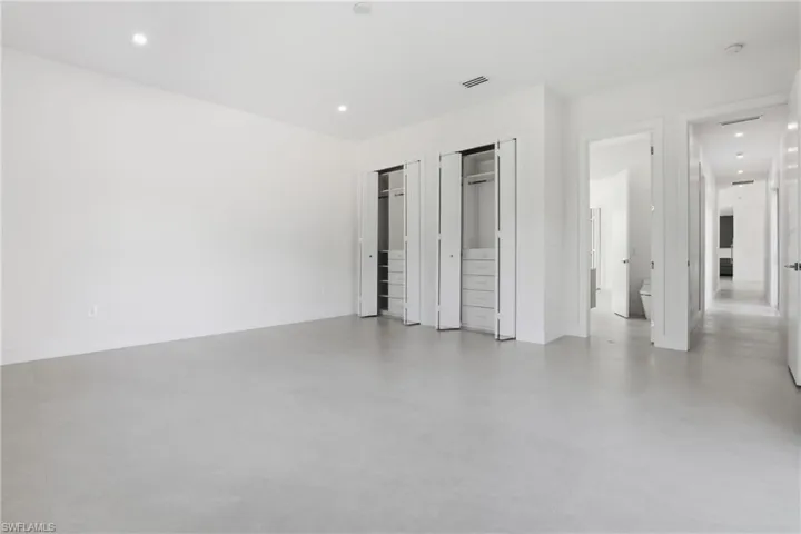 Unfurnished bedroom with two closets, recessed lighting, and finished concrete flooring