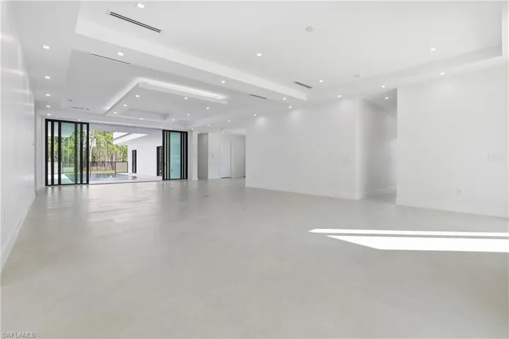 Empty room with a tray ceiling, recessed lighting, and finished concrete flooring