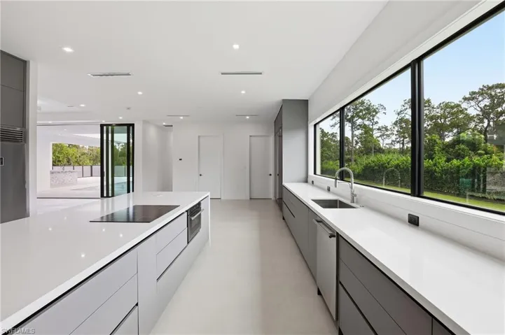Kitchen with modern cabinets, gray cabinetry, stainless steel appliances, recessed lighting, and light stone counters