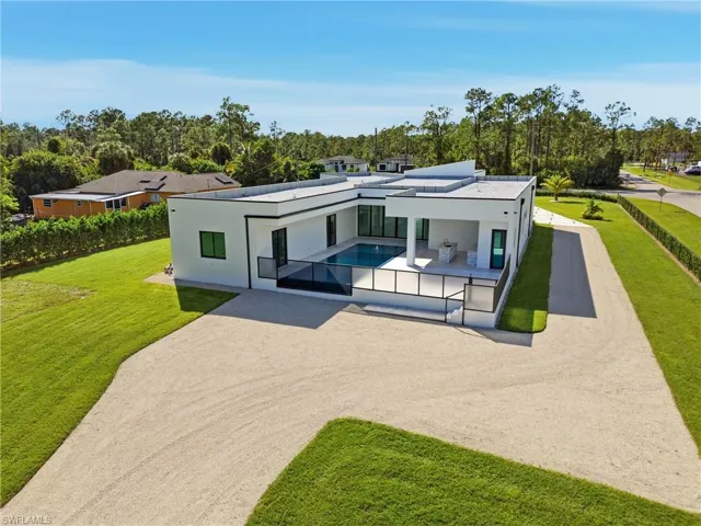 View of front of house featuring a patio area, stucco siding, and view of wooded area