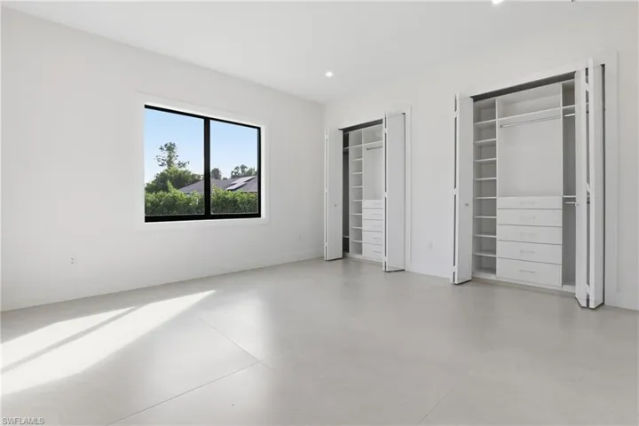 Unfurnished bedroom featuring two closets, recessed lighting, and finished concrete flooring