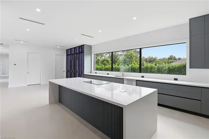 Kitchen with gray cabinetry, modern cabinets, light stone countertops, a kitchen island, and recessed lighting
