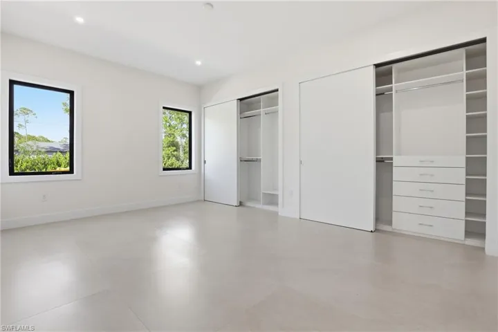 Unfurnished bedroom with multiple closets, recessed lighting, and concrete floors