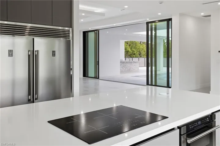 Kitchen with black electric stovetop, stainless steel built in refrigerator, and recessed lighting